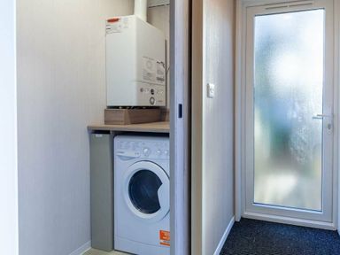 a laundry area with a washing machine and a door leading outside at Kelling Heath Holiday Park - Holiday Accommodation 16221 in Holt