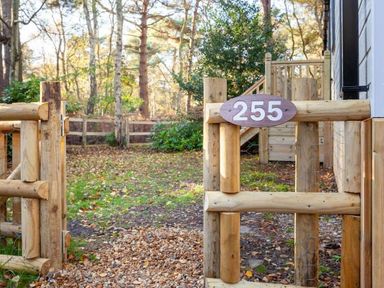 a wooden gate with the number 255 in a forested area at Kelling Heath Holiday Park - Holiday Accommodation 16221, Holt