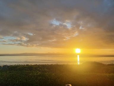 a sunset over the water with clouds and mountains in the background at Hafan y Mor Haven - Holiday Accommodation 16251 Pwllheli