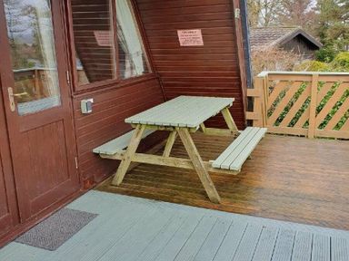 a wooden picnic table on a deck outside a cabin at Hafan y Mor Haven - Holiday Accommodation 16279 Pwllheli