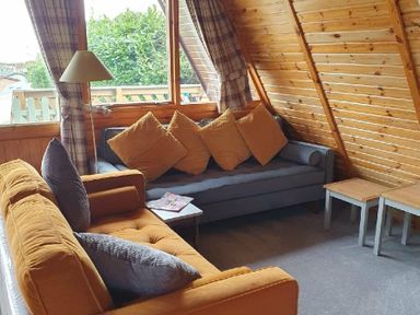 a seating area with two sofas and wooden tables at Hafan y Mor Haven - Holiday Accommodation 16279, Pwllheli