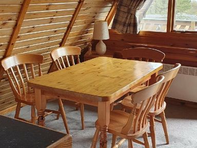 a wooden dining table with four chairs in an attic room at Hafan y Mor Haven - Holiday Accommodation 16279, Pwllheli