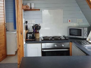 a kitchen with an oven, microwave, and sink at Hafan y Mor Haven - Holiday Accommodation 16279 Pwllheli