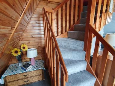 a stairway with wooden railing and carpet, along with a lamp and flowers in a corner at Hafan y Mor Haven - Holiday Accommodation 16279 Pwllheli