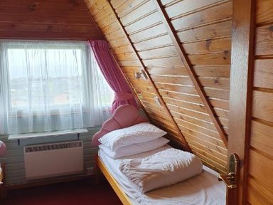 a bedroom with slanted wooden walls, two beds, and a window with curtains at Hafan y Mor Haven - Holiday Accommodation 16279 in Pwllheli