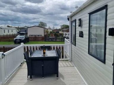 a table and chairs on a deck with a view of mobile homes at Unity Holiday Resort - Holiday Accommodation 16507, Brean, Somerset, United Kingdom