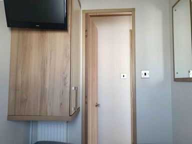 a room with a wall-mounted TV, a door, and a mirror at Unity Holiday Resort - Holiday Accommodation 16507, Brean, Somerset, United Kingdom