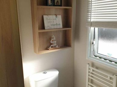 a bathroom with a shelf holding decor items and a toilet at Unity Holiday Resort - Holiday Accommodation 16507, Brean, Somerset, United Kingdom