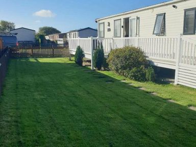 a lawn area with a caravan and hedges at Unity Holiday Resort - Holiday Accommodation 16507 in Brean, Somerset, United Kingdom