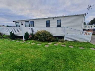 a holiday caravan with a deck and garden area at Unity Holiday Resort - Holiday Accommodation 16507 in Brean, Somerset, United Kingdom
