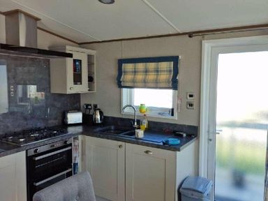 a kitchen with a sink, stove, and window at Lakeland Leisure Park - Holiday Accommodation 16942, Flookburgh