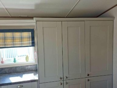 a kitchen area with grey cabinets and a window featuring a checked blind at Lakeland Leisure Park - Holiday Accommodation 16942, Flookburgh