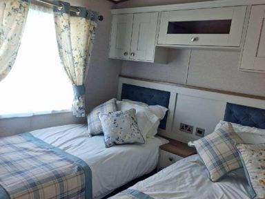 a bedroom with two beds and floral curtains at Lakeland Leisure Park - Holiday Accommodation 16942 in Flookburgh