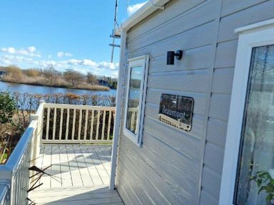 a wooden deck with a sign labeled Beaumont overlooking a body of water at Lakeland Leisure Park - Holiday Accommodation 16942, Flookburgh