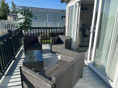 a balcony area with wicker chairs and a glass table at Lakeland Leisure Park - Holiday Accommodation 16942, Flookburgh