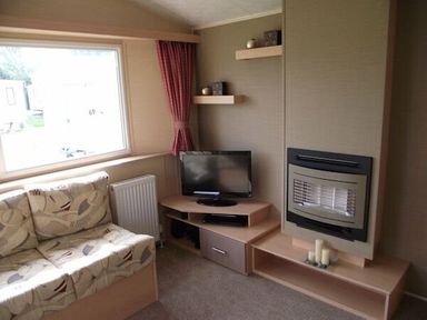 a living room with a sofa, television, and decorative shelves at Butlins Minehead - Holiday Accommodation 1700, Minehead