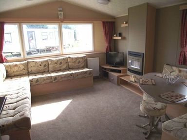 a living room with a sofa, TV unit, and dining table at Butlins Minehead - Holiday Accommodation 1700, Minehead