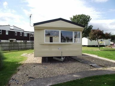 a caravan parked on gravel in a grassy area at Butlins Minehead - Holiday Accommodation 1700, Minehead