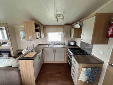 a kitchen with wooden cabinets and a stove at Hafan y Mor Haven - Holiday Accommodation 17436 Pwllheli