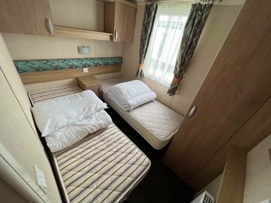 a bedroom with two single beds, a bedside table, and curtains at Hafan y Mor Haven - Holiday Accommodation 17436 in Pwllheli