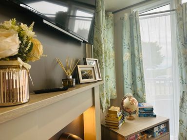 a living room with a TV, decorative flowers, curtains, and a globe at Ashbourne Heights Holiday Park - Holiday Accommodation 18103, Ashbourne