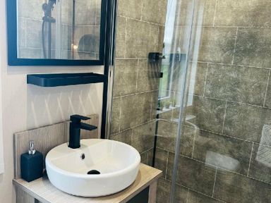 a bathroom with a sink, black faucet, and a glass shower at Ashbourne Heights Holiday Park - Holiday Accommodation 18103 Ashbourne