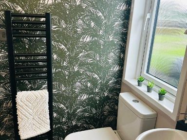 a bathroom with green palm leaf wallpaper and a towel rack next to a toilet at Ashbourne Heights Holiday Park - Holiday Accommodation 18103, Ashbourne