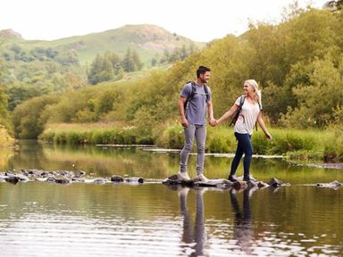 a couple walking on stones in a river surrounded by greenery at Ashbourne Heights Holiday Park - Holiday Accommodation 18103 Ashbourne