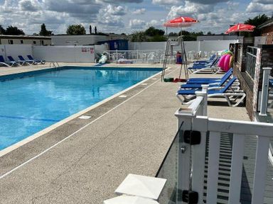 a swimming pool with lounge chairs and umbrellas at Breydon Water Holiday Park - Holiday Accommodation 18490 Great Yarmouth