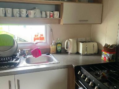 a kitchen counter with a sink, kettle, toaster, and various cleaning supplies at Breydon Water Holiday Park - Holiday Accommodation 18490 in Great Yarmouth