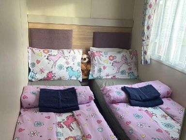 a bedroom with two single beds covered in pink unicorn bedding at Breydon Water Holiday Park - Holiday Accommodation 18490, Great Yarmouth