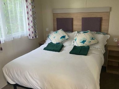 a bedroom with a double bed and decorative pillows at Breydon Water Holiday Park - Holiday Accommodation 18490 in Great Yarmouth