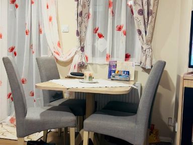 a dining area with a small table and four gray chairs at Breydon Water Holiday Park - Holiday Accommodation 18490 in Great Yarmouth