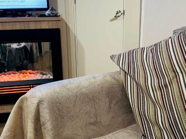 a cozy seating area with a patterned cushion and an electric fireplace at Breydon Water Holiday Park - Holiday Accommodation 18490 in Great Yarmouth