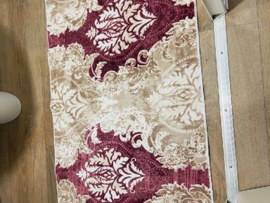 a patterned rug with burgundy and beige designs on a wooden floor at Breydon Water Holiday Park - Holiday Accommodation 18490, Great Yarmouth