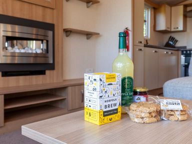 a wooden table with tea, apple juice, jam, and cookies in a living area at Kelling Heath Holiday Park - Holiday Accommodation 18663, Holt