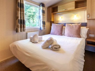 a bedroom with a double bed featuring pillows and towels at Kelling Heath Holiday Park - Holiday Accommodation 18663 in Holt