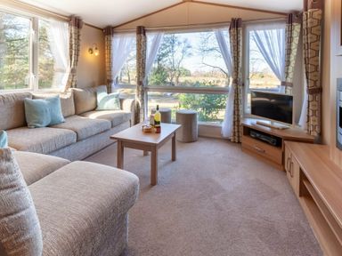 a living room with a sofa, coffee table, and TV at Kelling Heath Holiday Park - Holiday Accommodation 18663, Holt