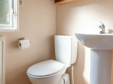 a bathroom featuring a toilet and a sink at Kelling Heath Holiday Park - Holiday Accommodation 18663 in Holt