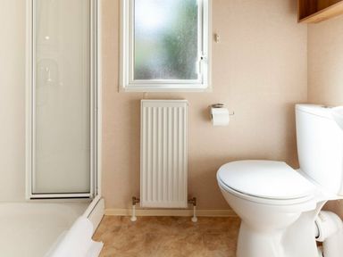 a bathroom with a shower, toilet, and radiator at Kelling Heath Holiday Park - Holiday Accommodation 18663 in Holt
