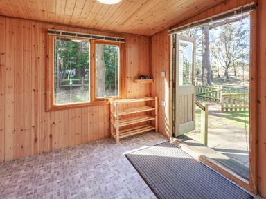 a room with wood paneling, a door open to the outside, and a shelf near the window at Kelling Heath Holiday Park - Holiday Accommodation 18663, Holt