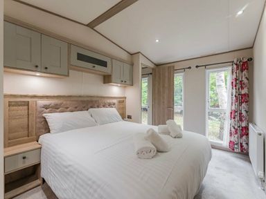a bedroom with a king size bed and bedside tables at Kelling Heath Holiday Park - Holiday Accommodation 18664, Holt