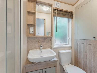 a bathroom with a sink, toilet, and window at Kelling Heath Holiday Park - Holiday Accommodation 18664, Holt