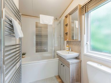 a bathroom with a shower, bathtub, and sink with cabinetry at Kelling Heath Holiday Park - Holiday Accommodation 18664 in Holt