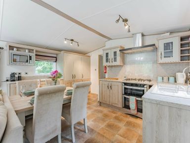 a kitchen and dining area with a table and chairs at Kelling Heath Holiday Park - Holiday Accommodation 18664, Holt