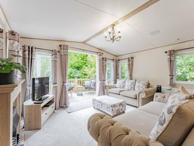 a living room with a sofa, armchair, and a television at Kelling Heath Holiday Park - Holiday Accommodation 18664 in Holt