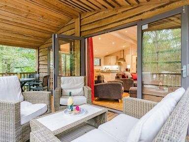 a seating area with wicker furniture and a view of a kitchen inside a cabin at Kelling Heath Holiday Park - Holiday Accommodation 18691 in Holt