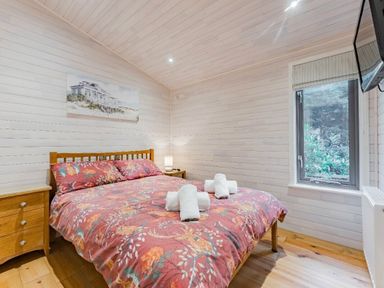 a bedroom with a double bed, nightstand, and window at Kelling Heath Holiday Park - Holiday Accommodation 18691, Holt