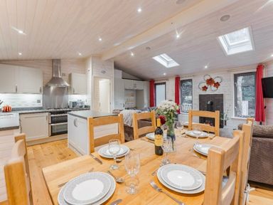 a dining area with a wooden table set for dinner in Kelling Heath Holiday Park - Holiday Accommodation 18691, Holt