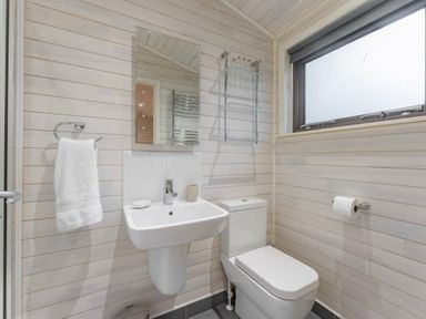 a bathroom with a sink, toilet, mirror, and towel rail at Kelling Heath Holiday Park - Holiday Accommodation 18691, Holt